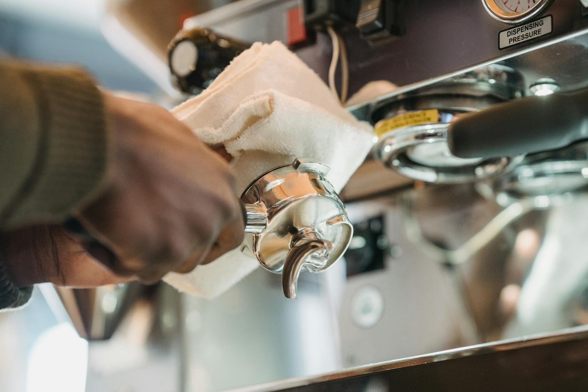 Barista czyści portafilter ekspresu do kawy miękką ściereczką
